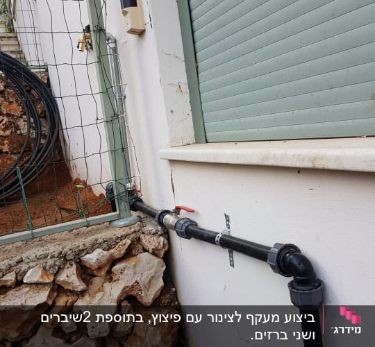 צינור מים שחור עם ברז על קיר חיצוני